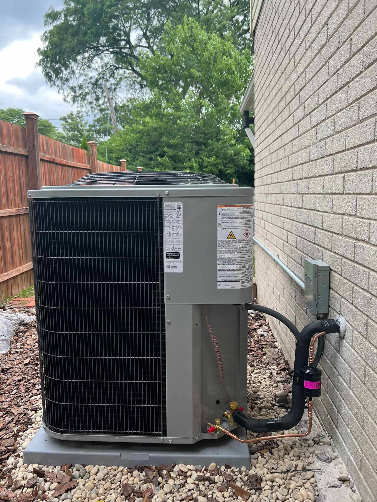 AMW technician measuring refrigerant pressure on an outdoor AC condenser unit